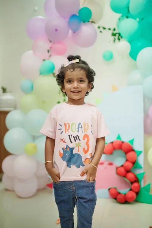 Girl in a party T-shirt in front of a balloon wall