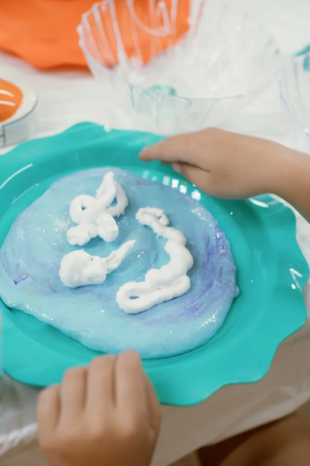A child shaping blue slime at a party workshop
